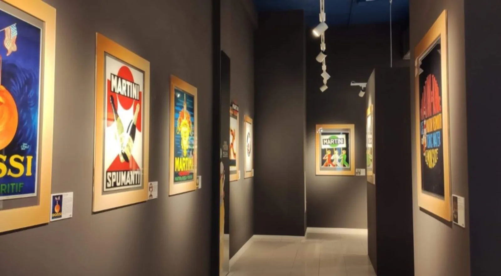 Corridoio della mostra Mondo Martini con i manifesti incorniciati alle pareti