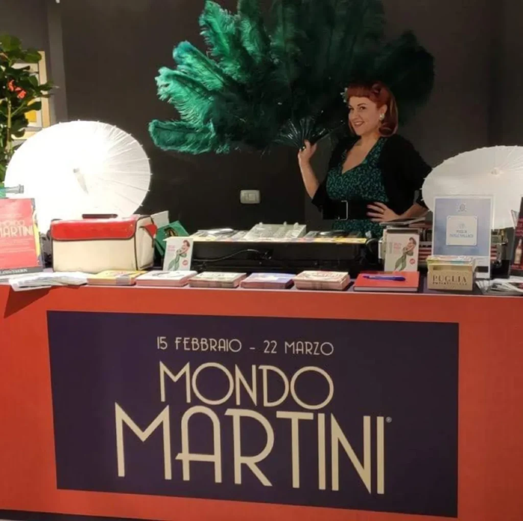 Stand della mostra Mondo Martini con figura in abito di piume verdi