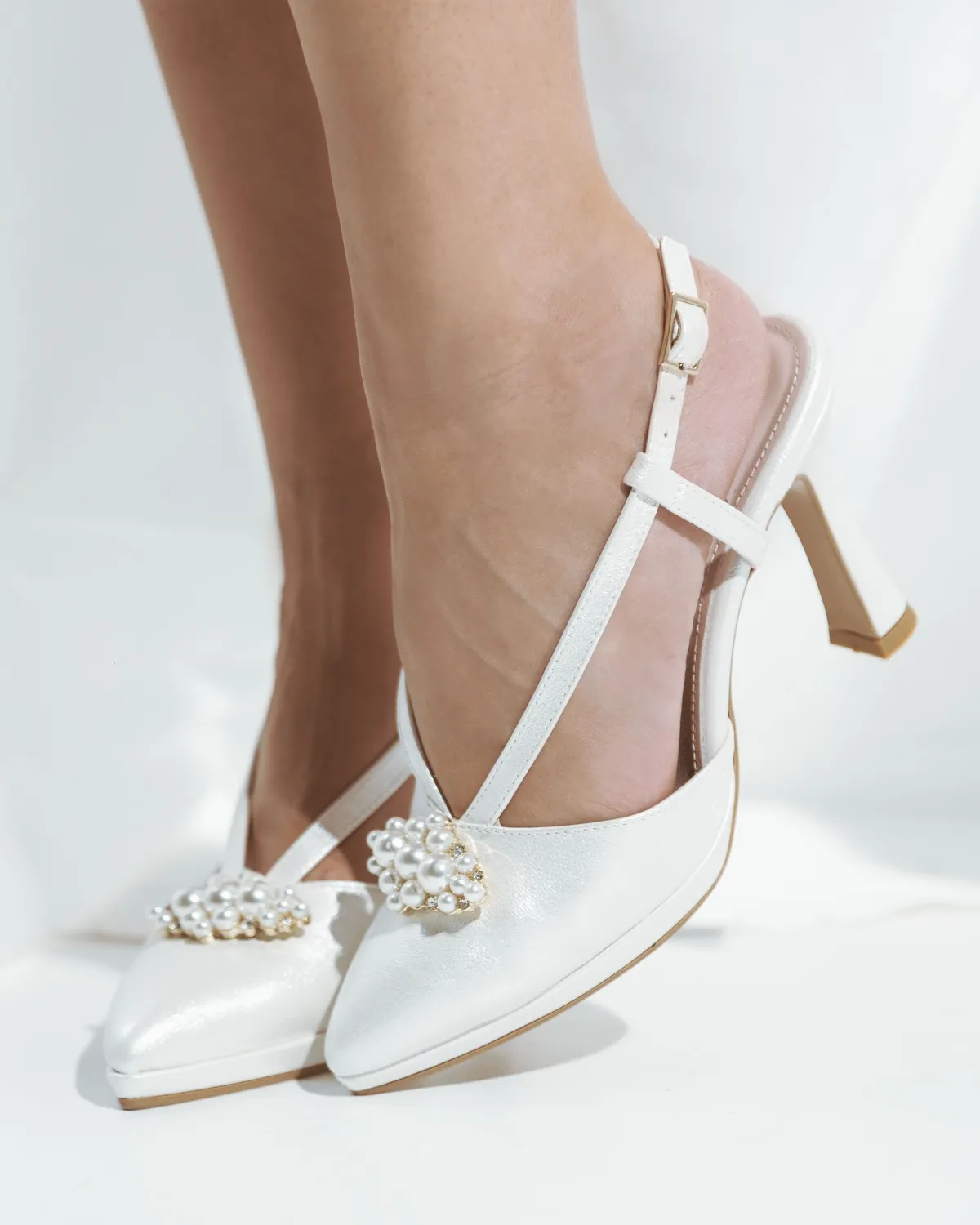Slingback bianche con il gioiello di perle sulla punta, foto in studio