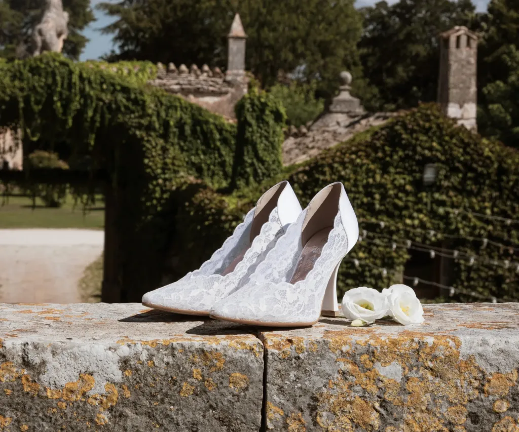 Décolleté da sposa in pizzo bianco appoggiate su un muretto di pietra in una masseria pugliese