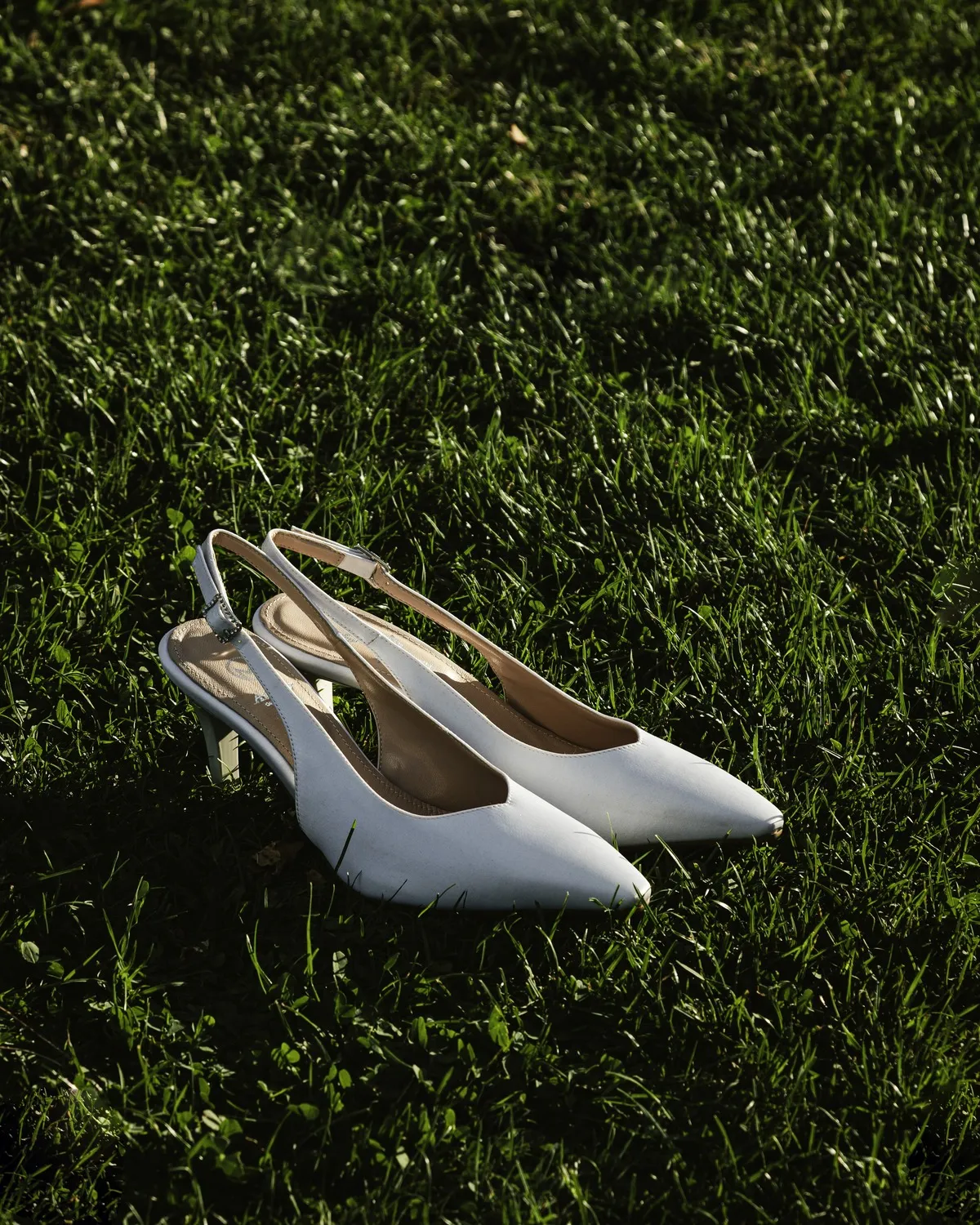 Slingback da sposa in raso bianco appoggiate sull'erba