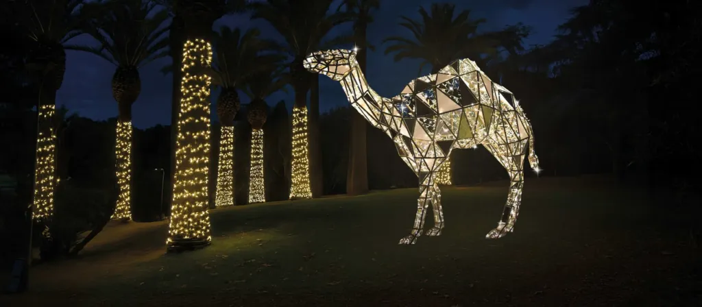Rendering con l'AI: un dromedario di luminarie Paulicelli tra le palme illuminate del Parco 2 Giugno di Bari, di notte