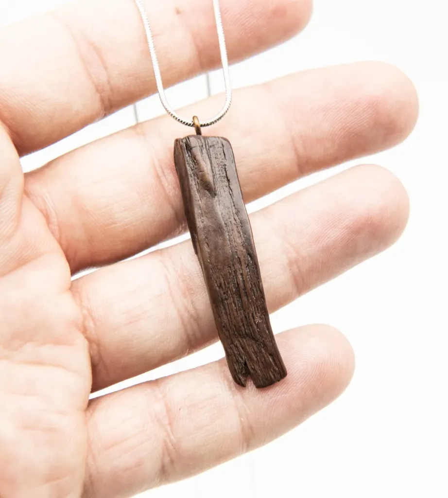 Pendente di legno con catenina d'argento tenuto nel palmo di una mano, gioielli Semiami