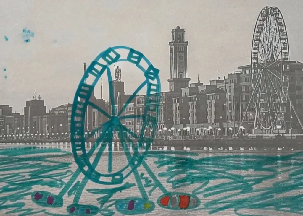 Una ruota panoramica disegnata a pennarello azzurro sul mare davanti al lungomare di Bari